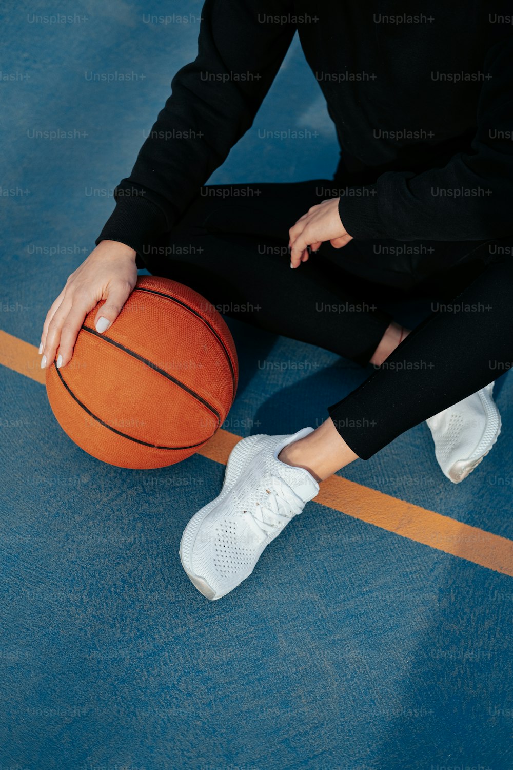 Una persona sentada en el suelo con una pelota de baloncesto
