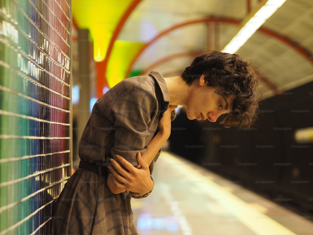 a man leaning against a wall in a subway station