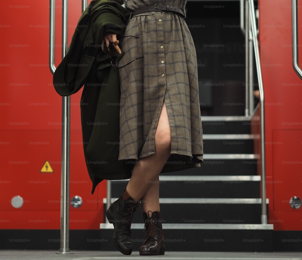 a woman in a dress and boots is walking down a set of stairs