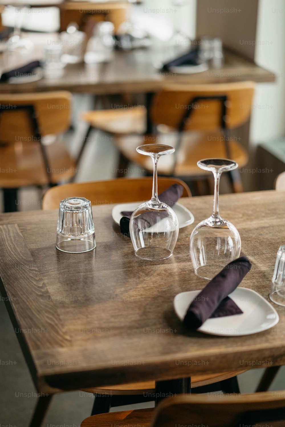 a wooden table topped with two wine glasses