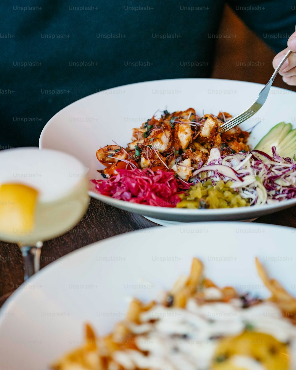 a person cutting into a salad with a knife