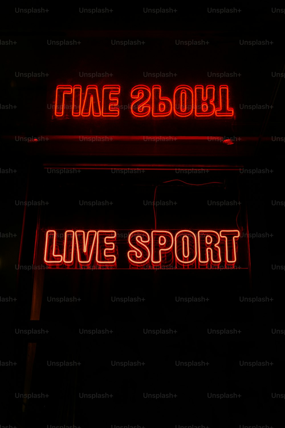 Eine Leuchtreklame, auf der Live-Sport in einem dunklen Raum steht