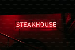 Un letrero de neón rojo que dice Steakhouse