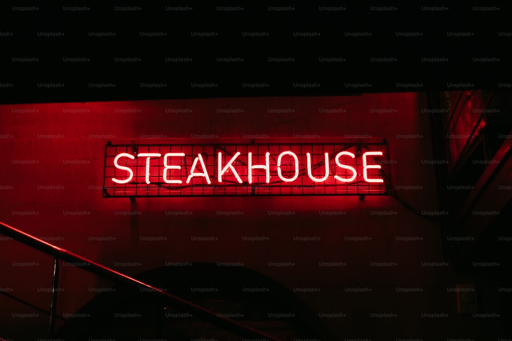 Un letrero de neón rojo que dice Steakhouse