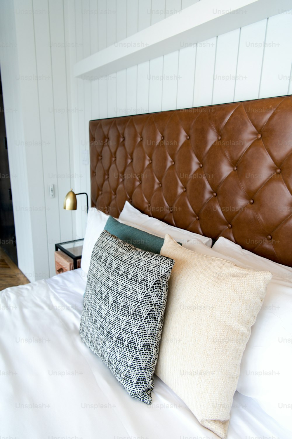 a bed with a brown leather headboard and pillows