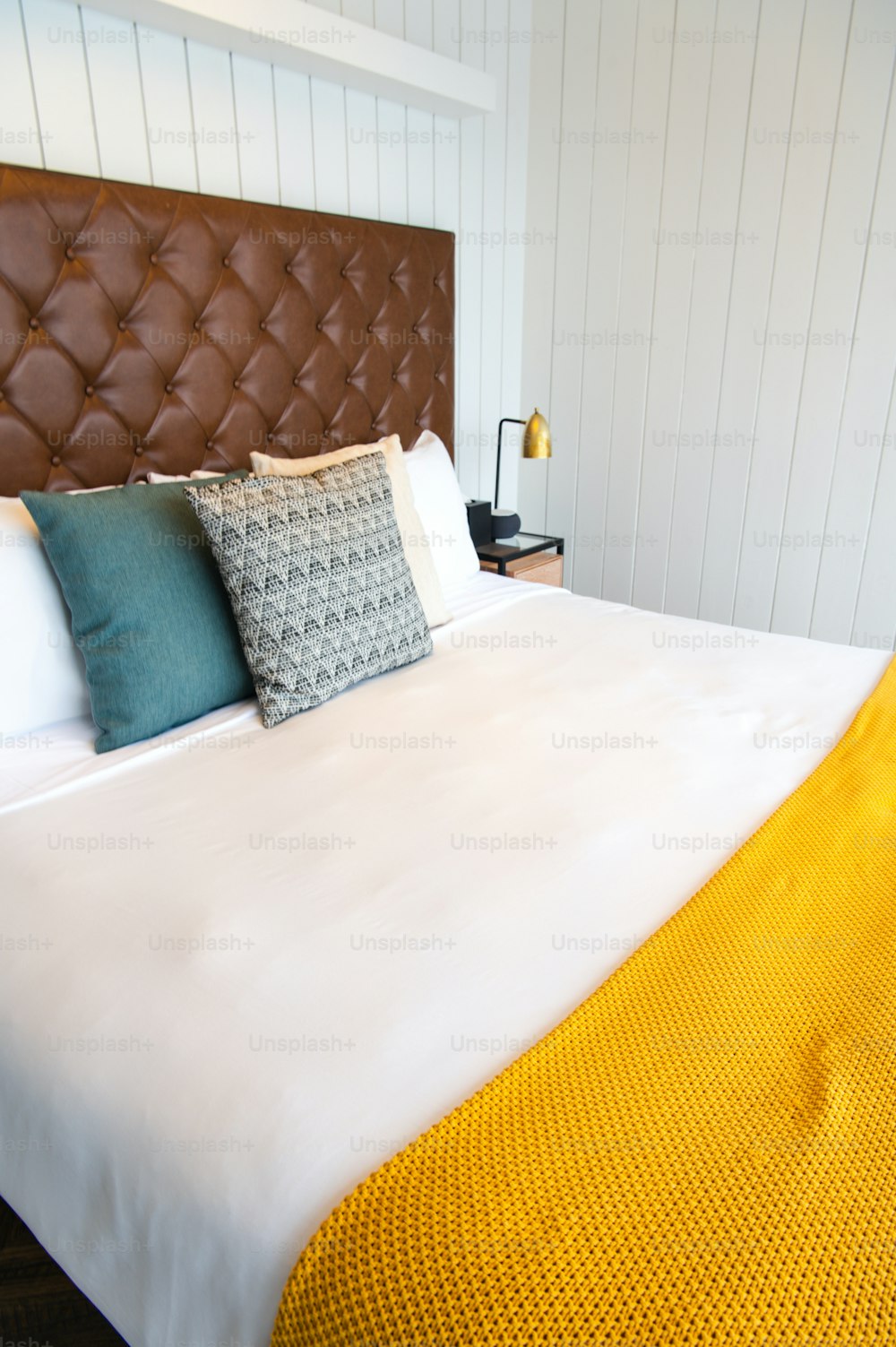una cama con cabecera marrón y una manta amarilla