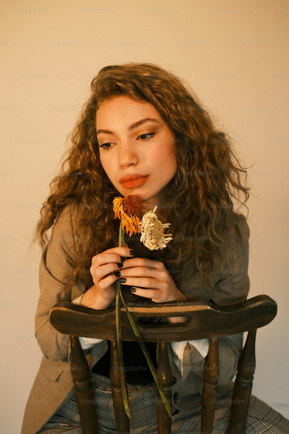 a woman sitting in a chair holding a flower