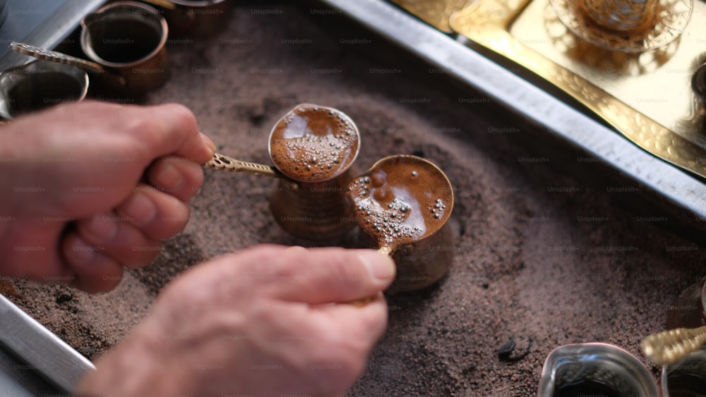 a person holding a spoon over a cup filled with liquid