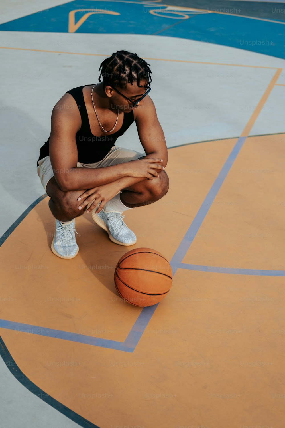 Une femme assise sur un terrain de basket-ball tenant un ballon de basket-ball