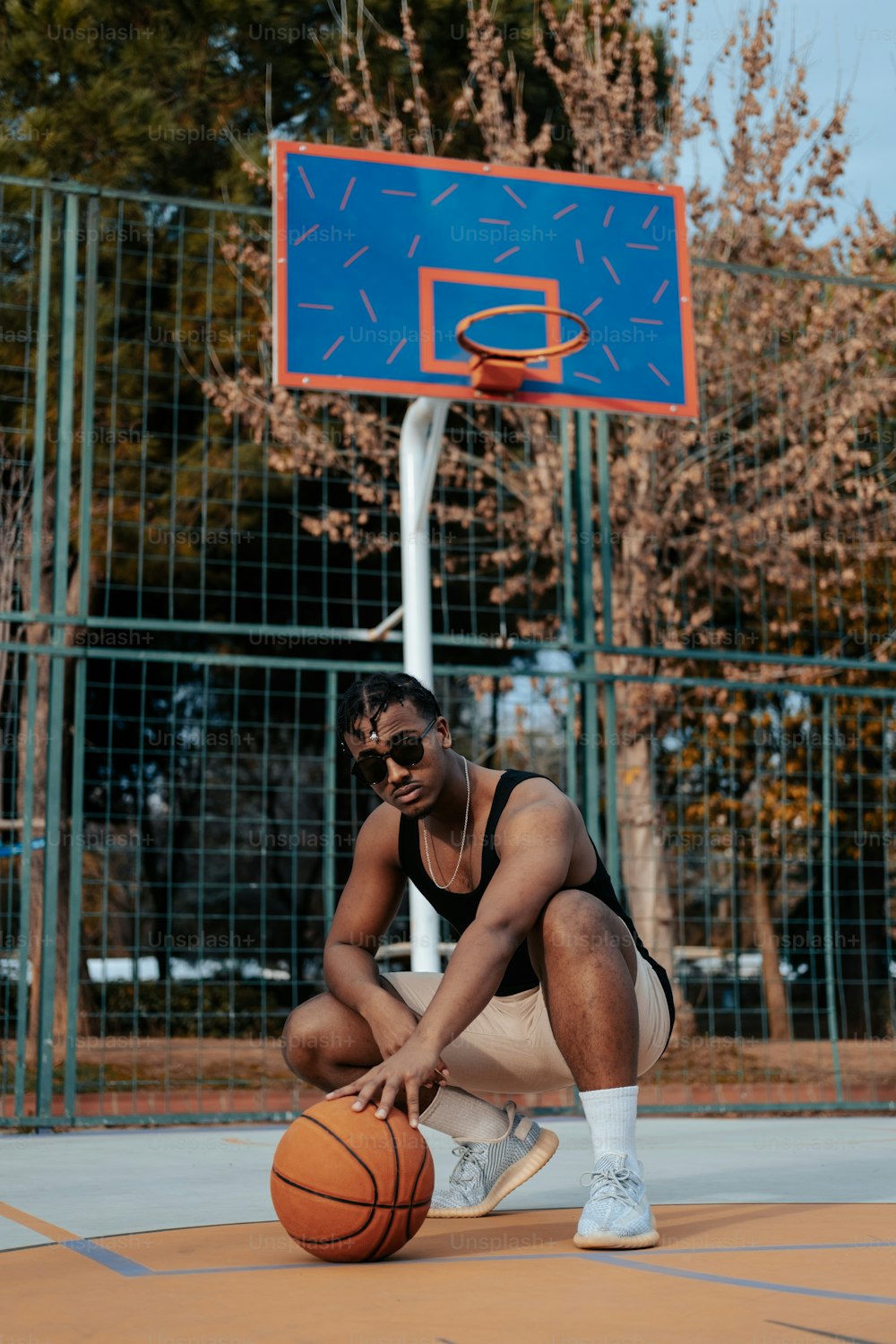 a man sitting on a basketball court while talking on a cell phone