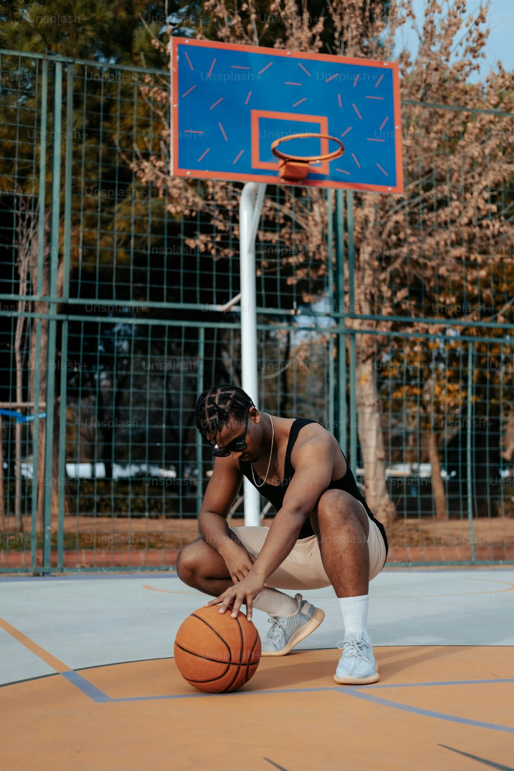 um homem ajoelhado ao lado de uma bola de basquete em uma quadra