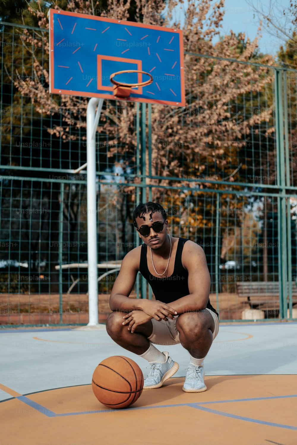 um homem ajoelhado ao lado de uma bola de basquete em uma quadra