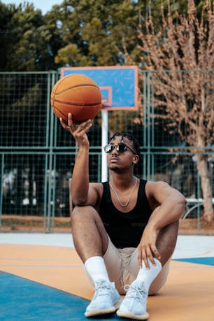 a man sitting on the ground holding a basketball