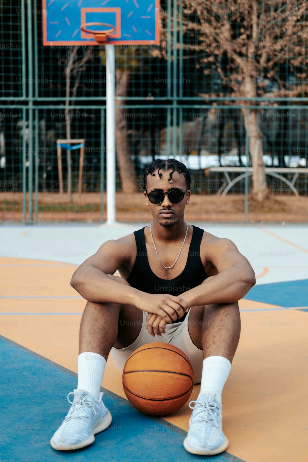 Un homme assis sur un terrain de basket-ball tenant un ballon de basket