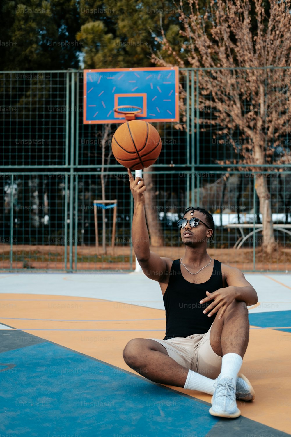 Un hombre sentado en el suelo con una pelota de baloncesto en la mano