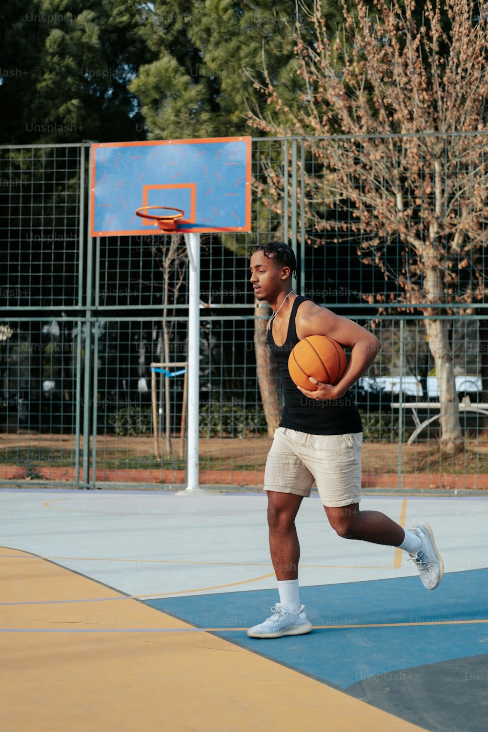 Un hombre sosteniendo una pelota de baloncesto encima de una cancha de baloncesto