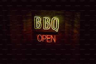 a neon sign that says bbq open in a dark room