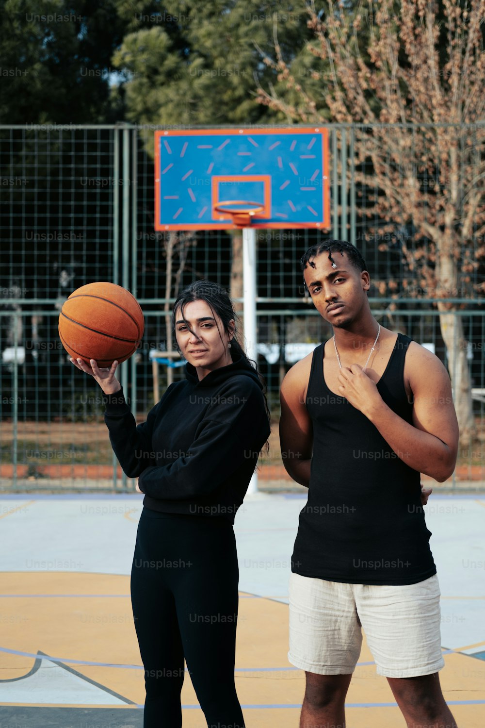 Un hombre y una mujer parados uno al lado del otro sosteniendo una pelota de baloncesto