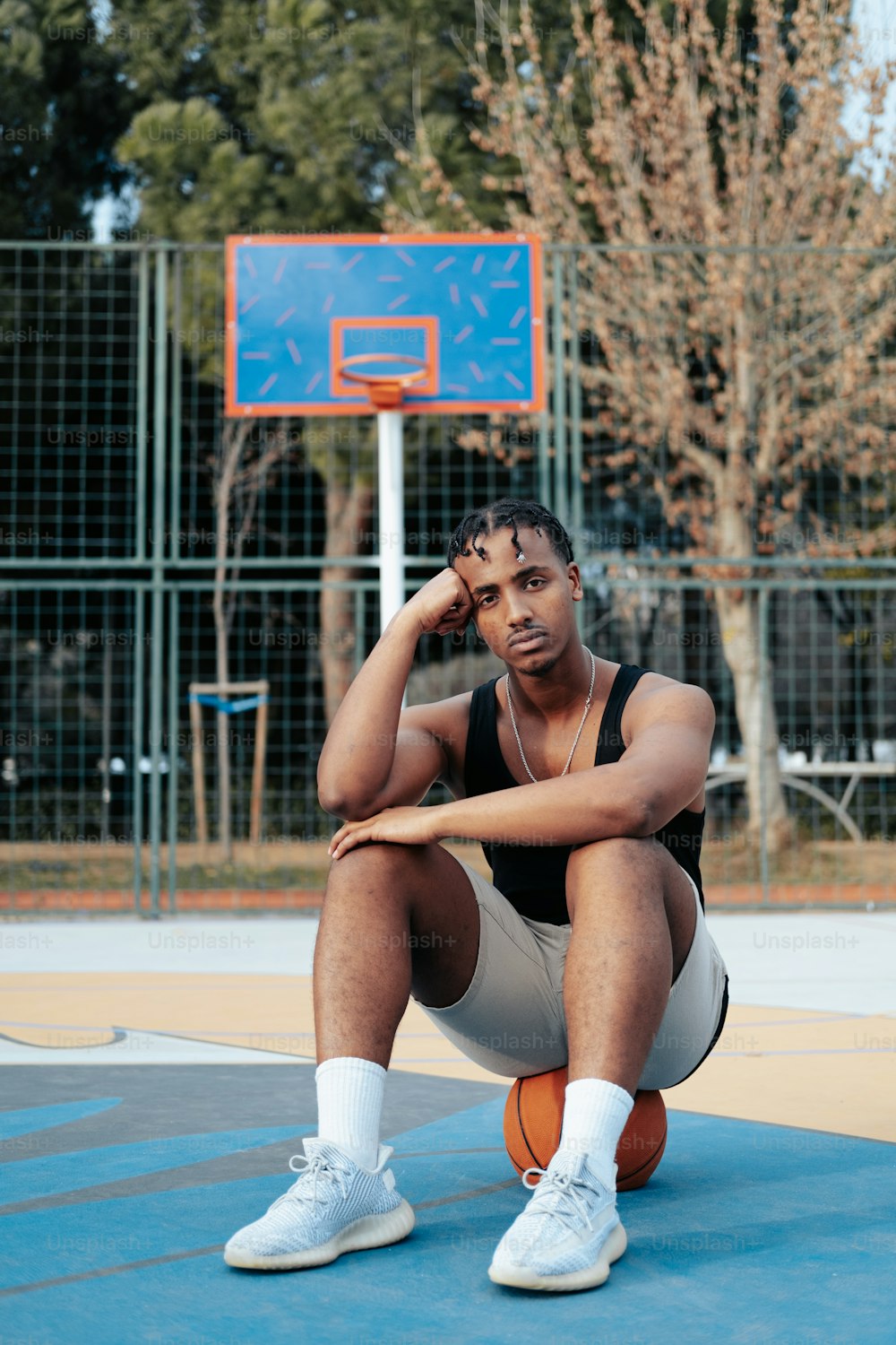 a man sitting on a basketball court holding a basketball