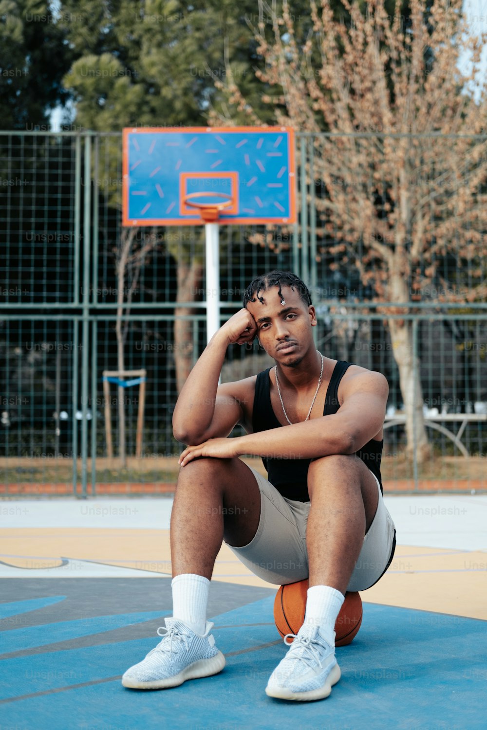 Un uomo seduto su un campo da basket con in mano un pallone da basket