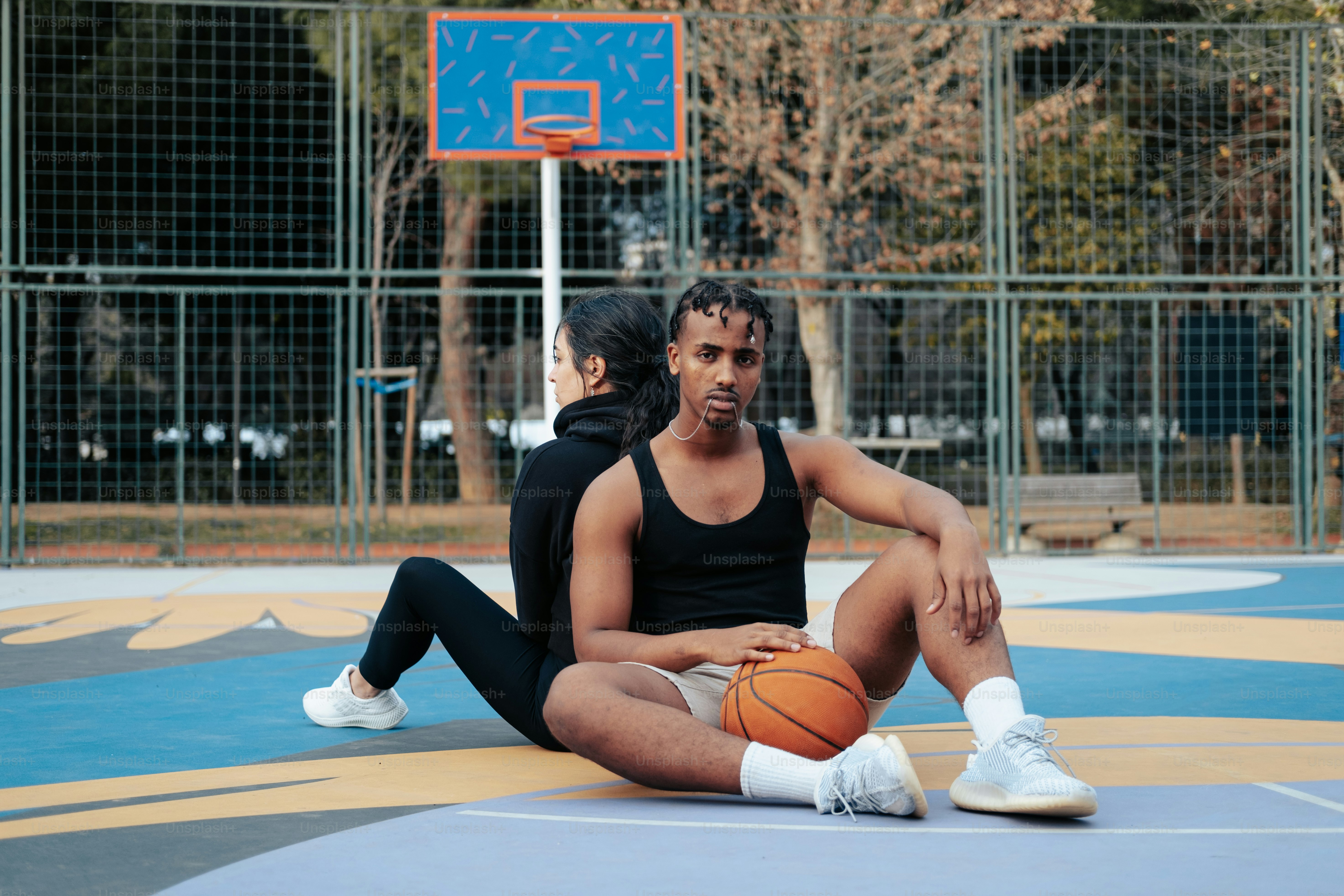 a man and a woman sitting on a basketball court