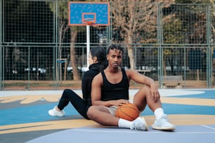 um homem e uma mulher sentados em uma quadra de basquete