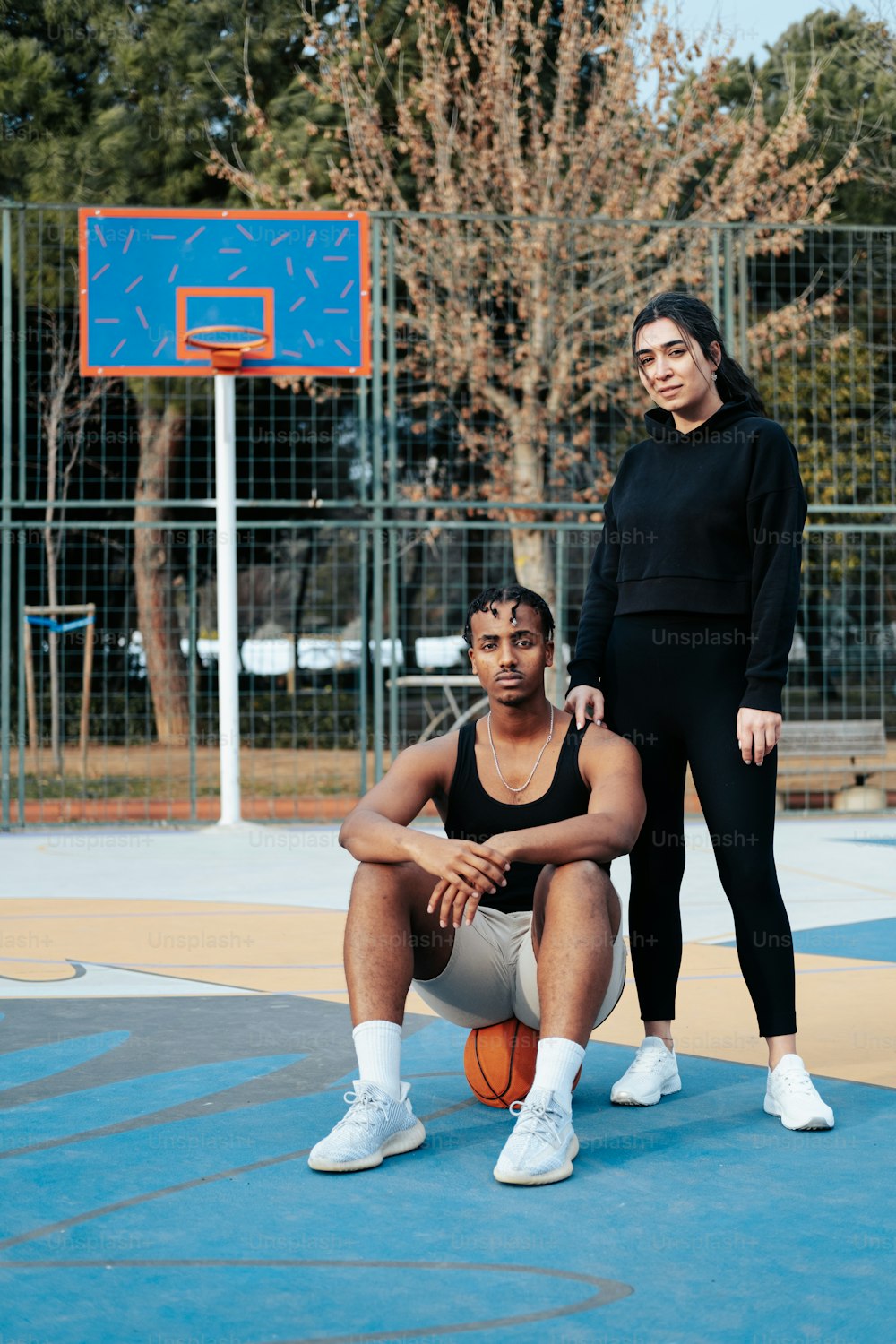 um casal de mulheres de pé um ao lado do outro em uma quadra de basquete