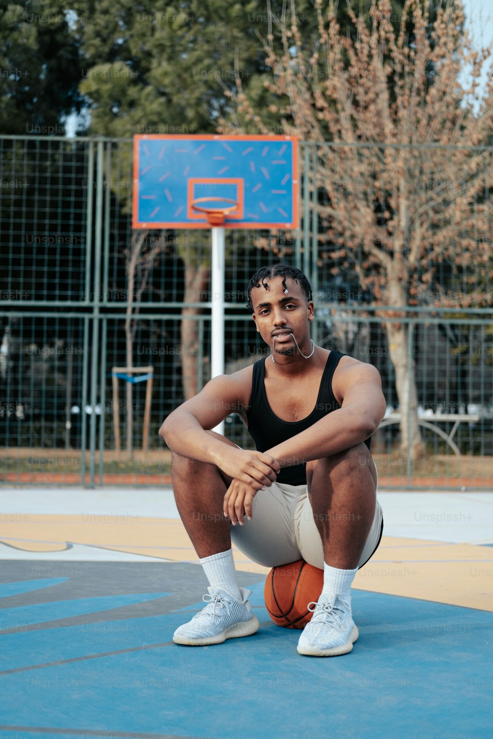 Un uomo seduto su un campo da basket con in mano un pallone da basket