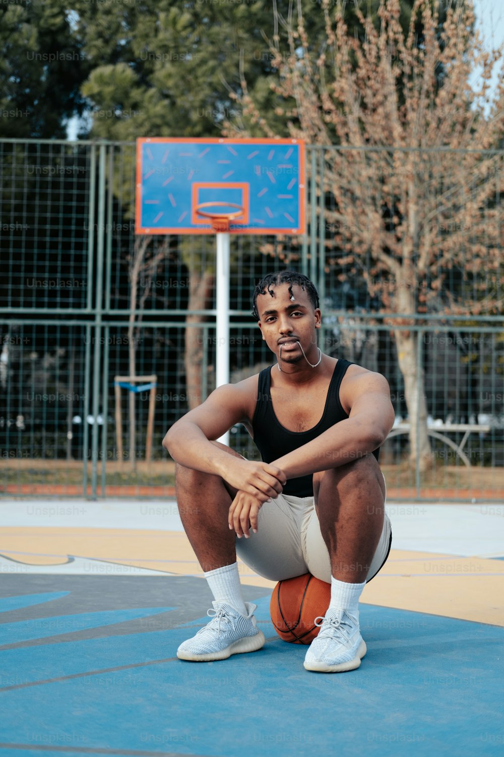 a man sitting on a basketball court holding a basketball