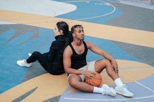 a man and a woman sitting on a basketball court