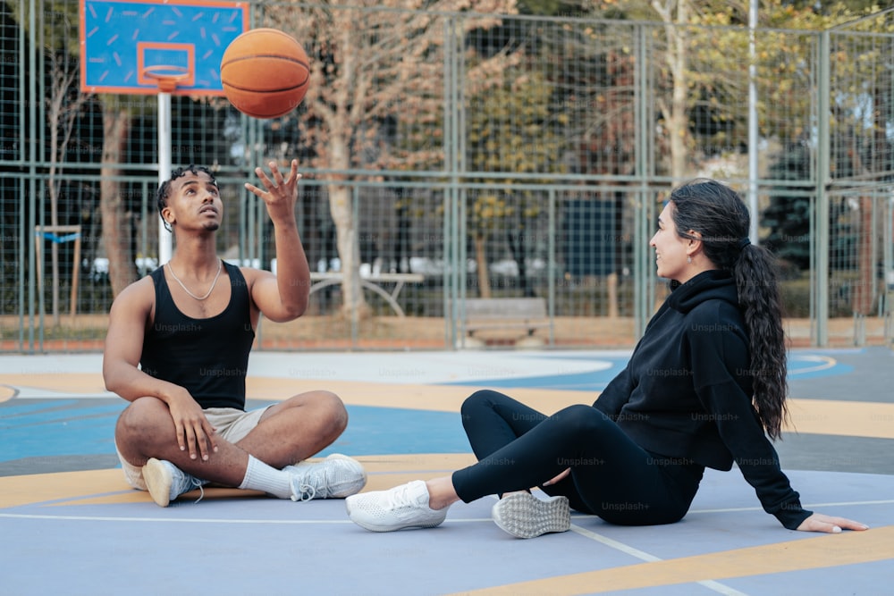 a couple of women sitting on top of a basketball court