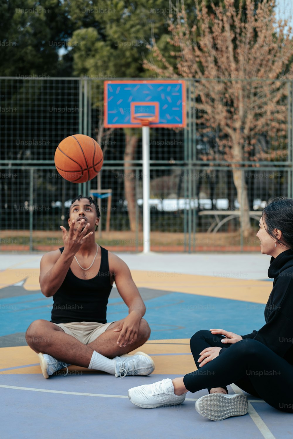 a couple of people sitting on a basketball court