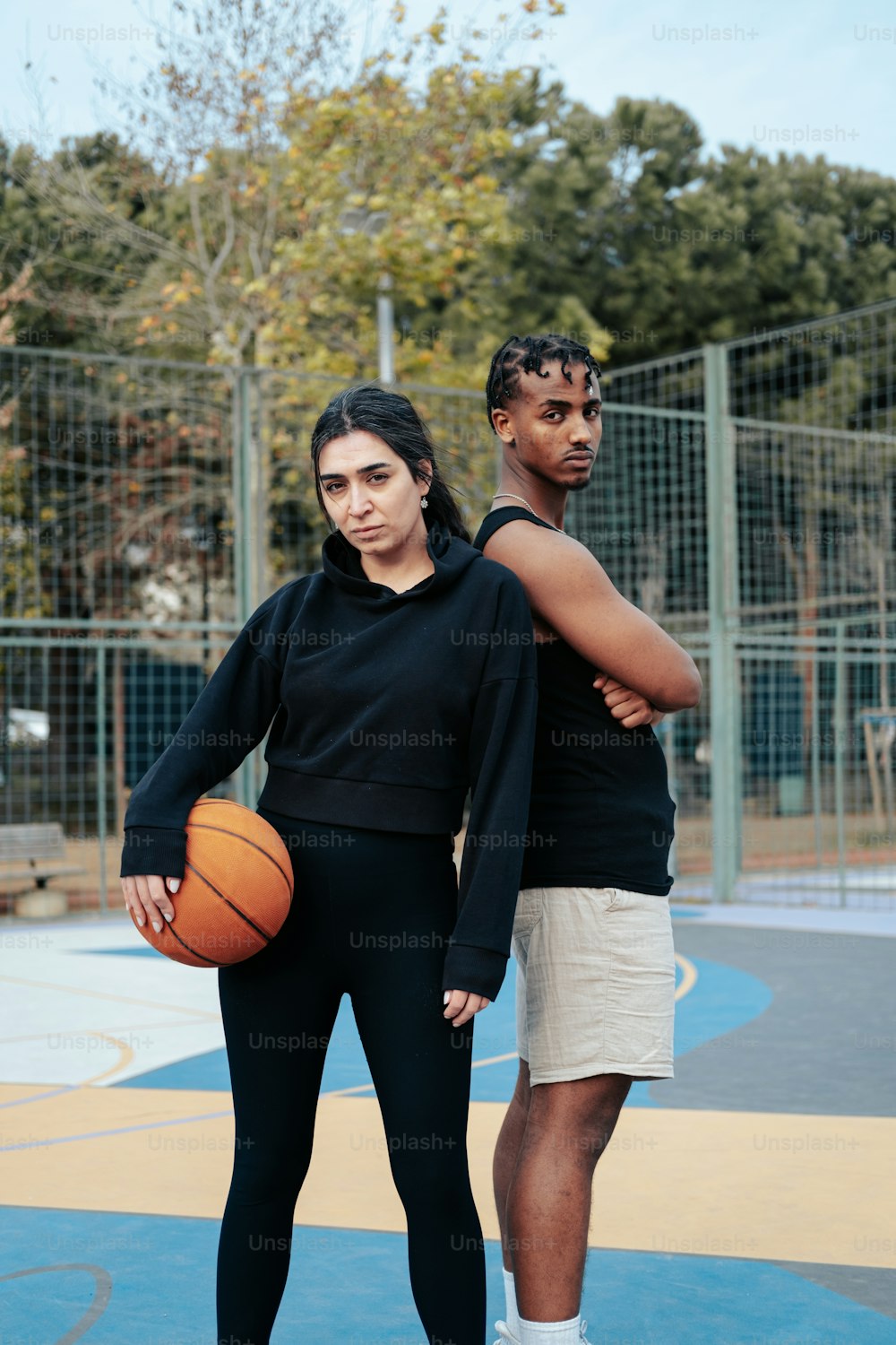 um homem e uma mulher em pé em uma quadra de basquete