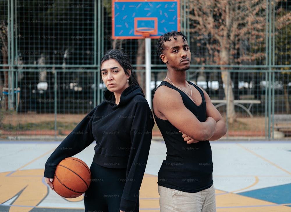 a man and a woman standing next to each other holding a basketball