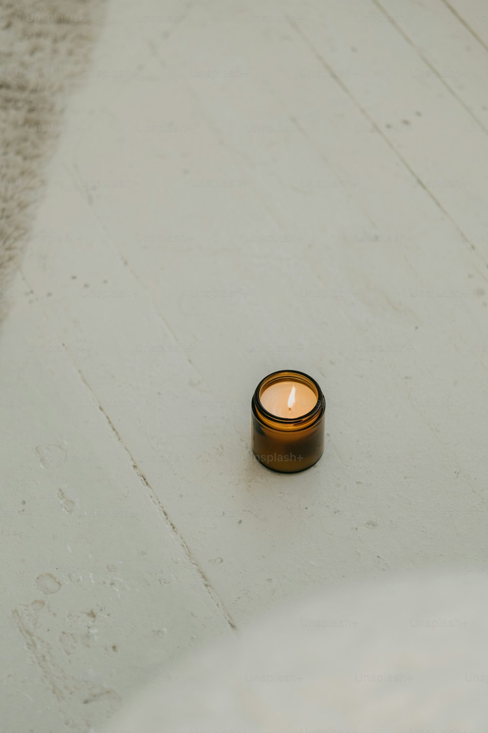 una piccola candela seduta su una superficie bianca