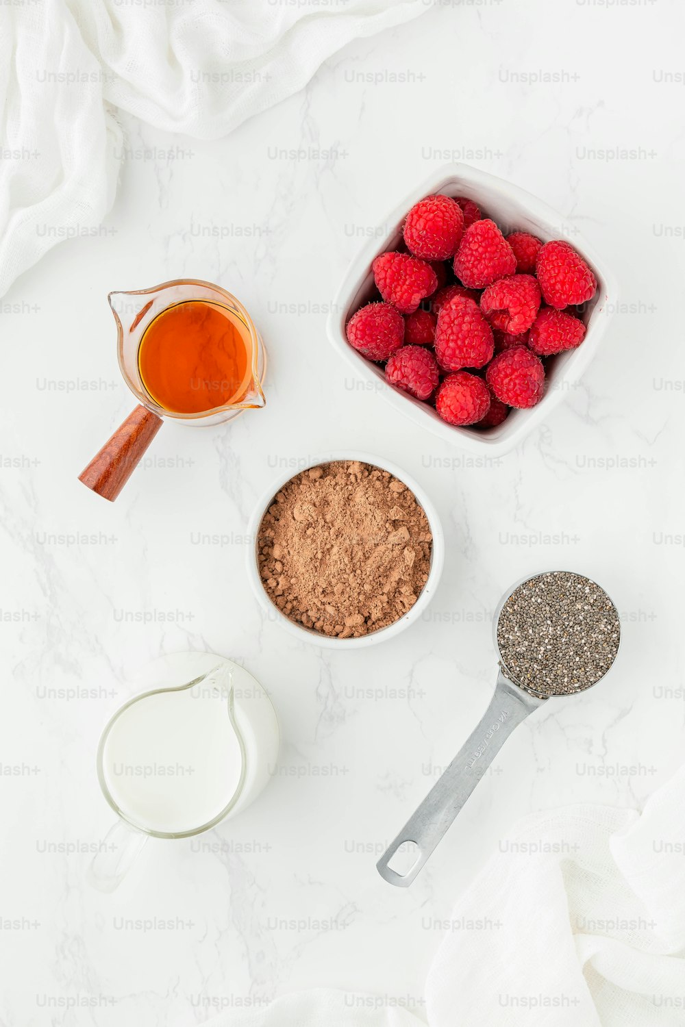 raspberries, milk, and other ingredients on a white surface