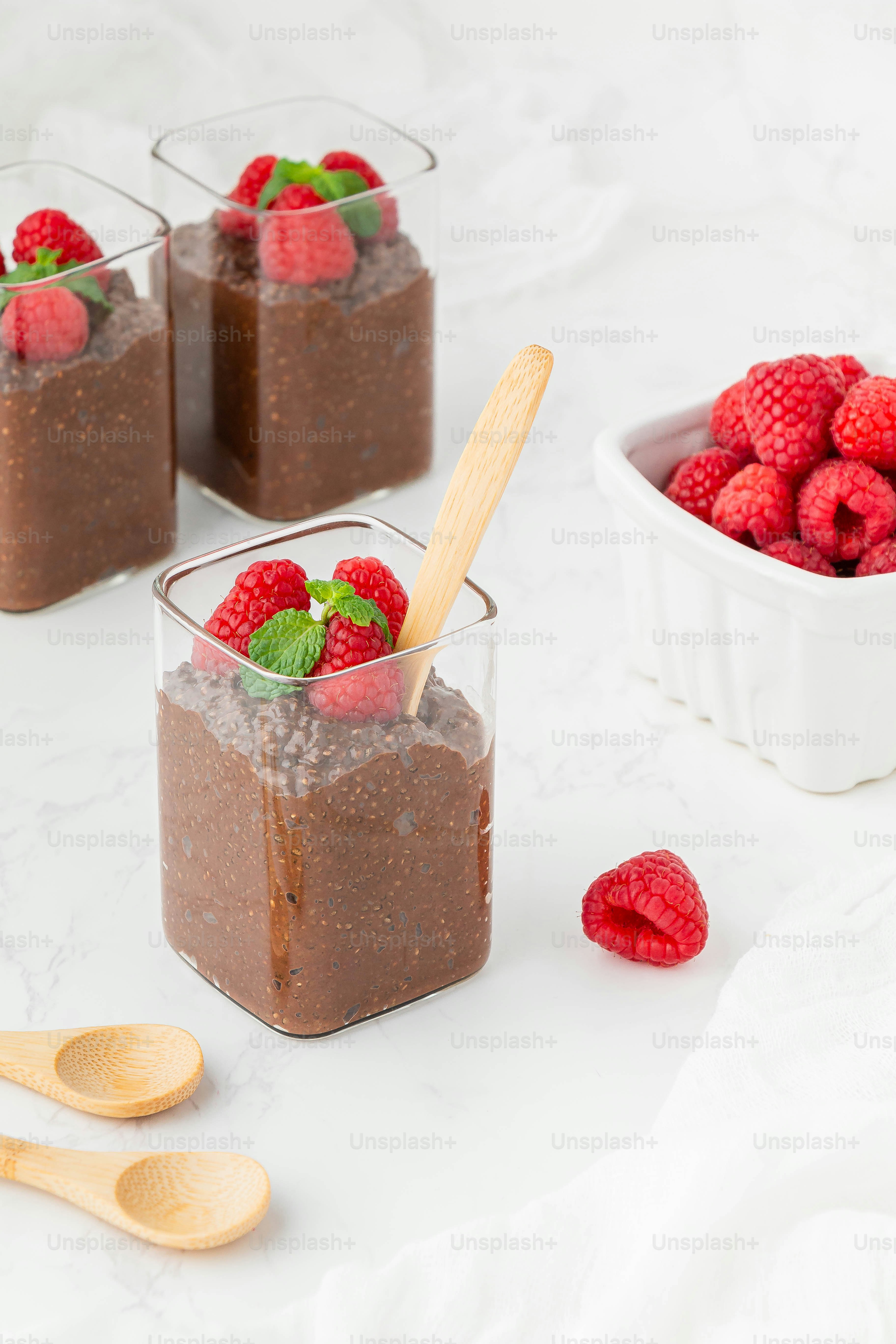 Raspberries and chocolate pudding in small glass containers with spoons