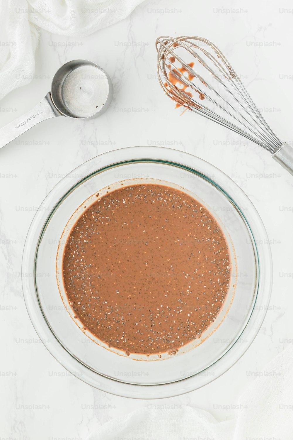 a glass bowl filled with brown liquid next to a whisk and whis