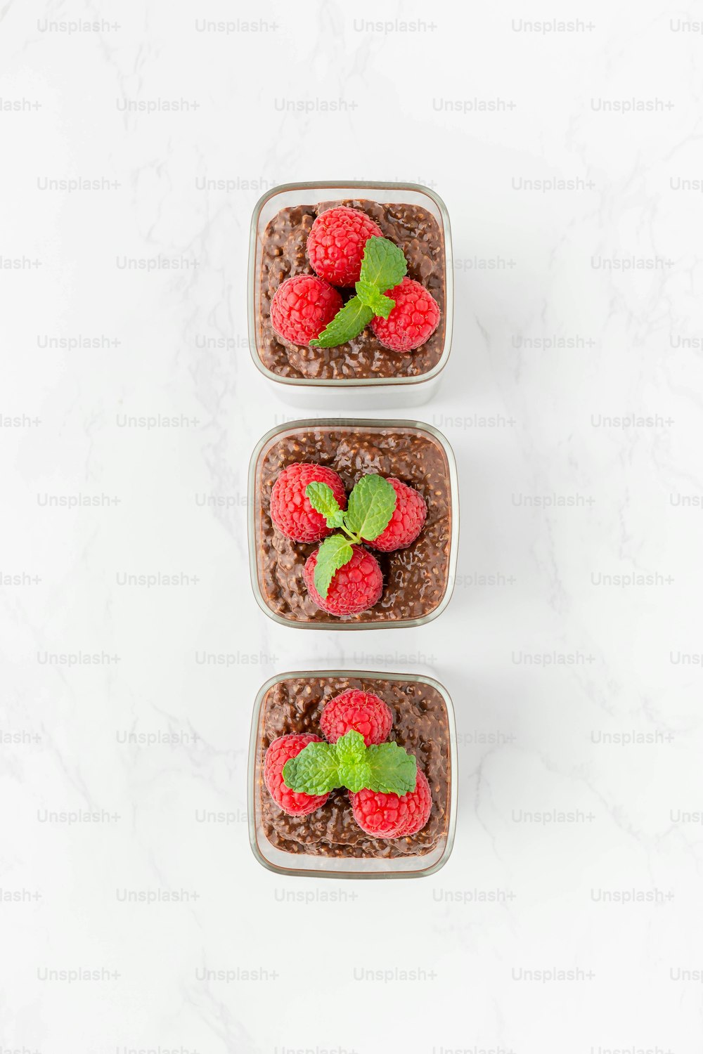 three plastic containers filled with brownies and raspberries