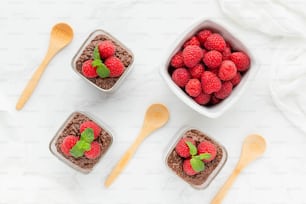 three bowls of chocolate pudding with raspberries in them