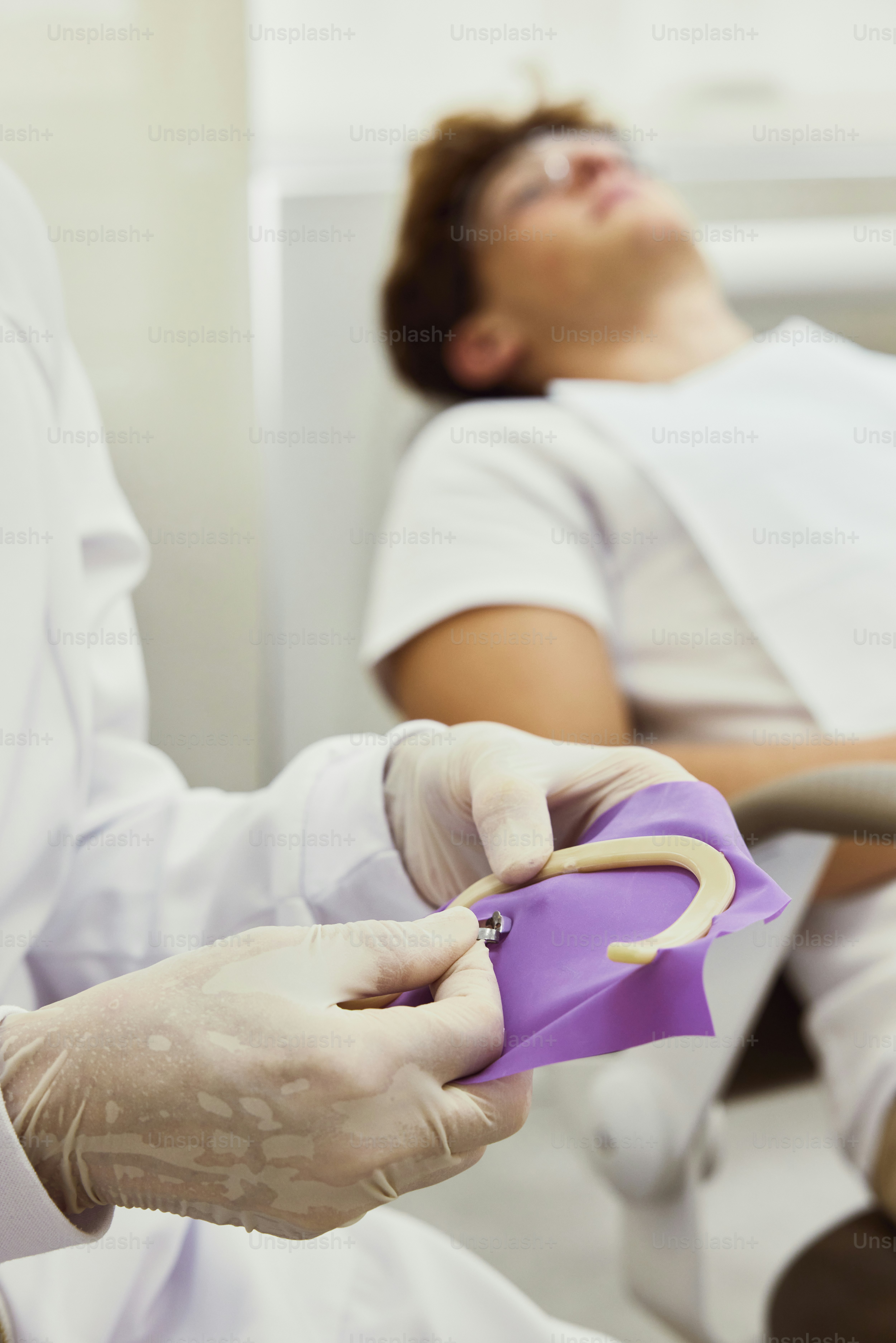 A person in a white lab coat is holding a purple object photo ...