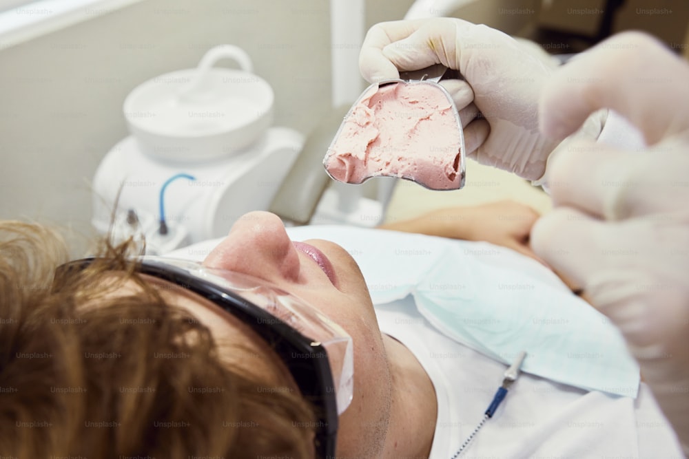 Un uomo sdraiato su una poltrona del dentista mentre tiene in mano un pezzo di gelato
