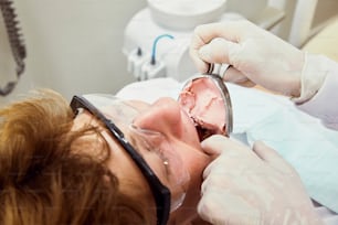Eine Frau lässt ihre Zähne von einem Zahnarzt reinigen