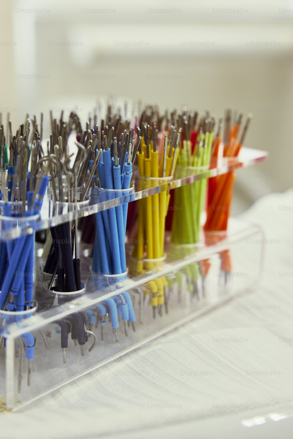 Un recipiente de plástico lleno de muchos bolígrafos de diferentes colores