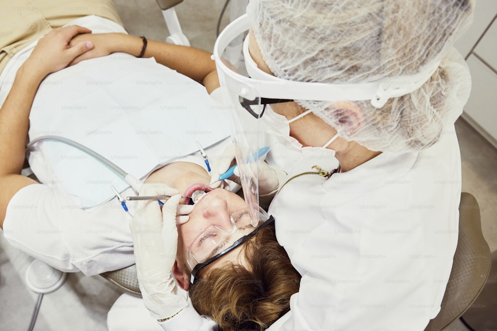 Una donna sdraiata su una poltrona da dentista con la bocca aperta