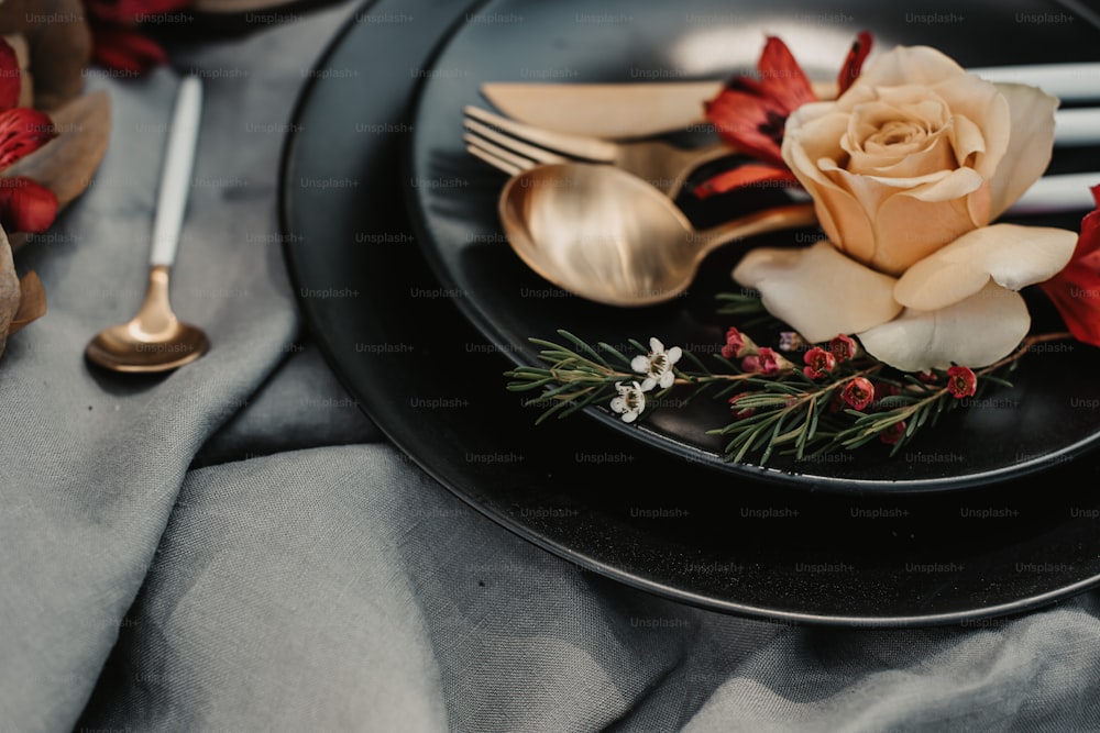 a black plate topped with a rose and silverware