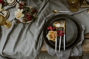 a black plate topped with flowers next to a fork and knife