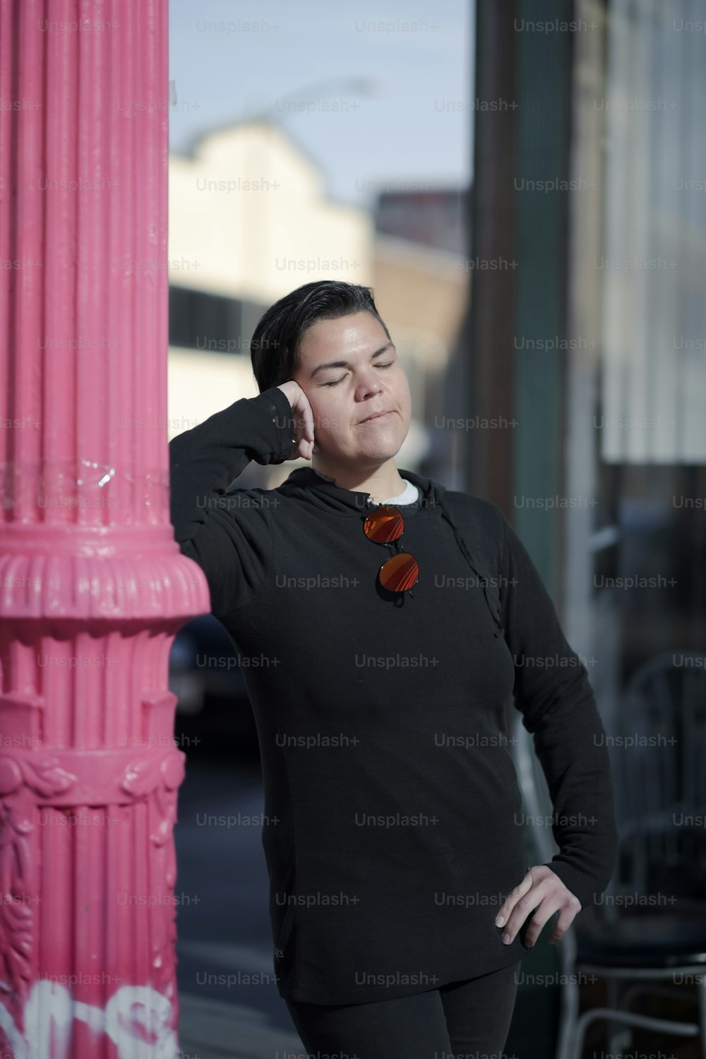 a woman leaning against a pink pole talking on a cell phone