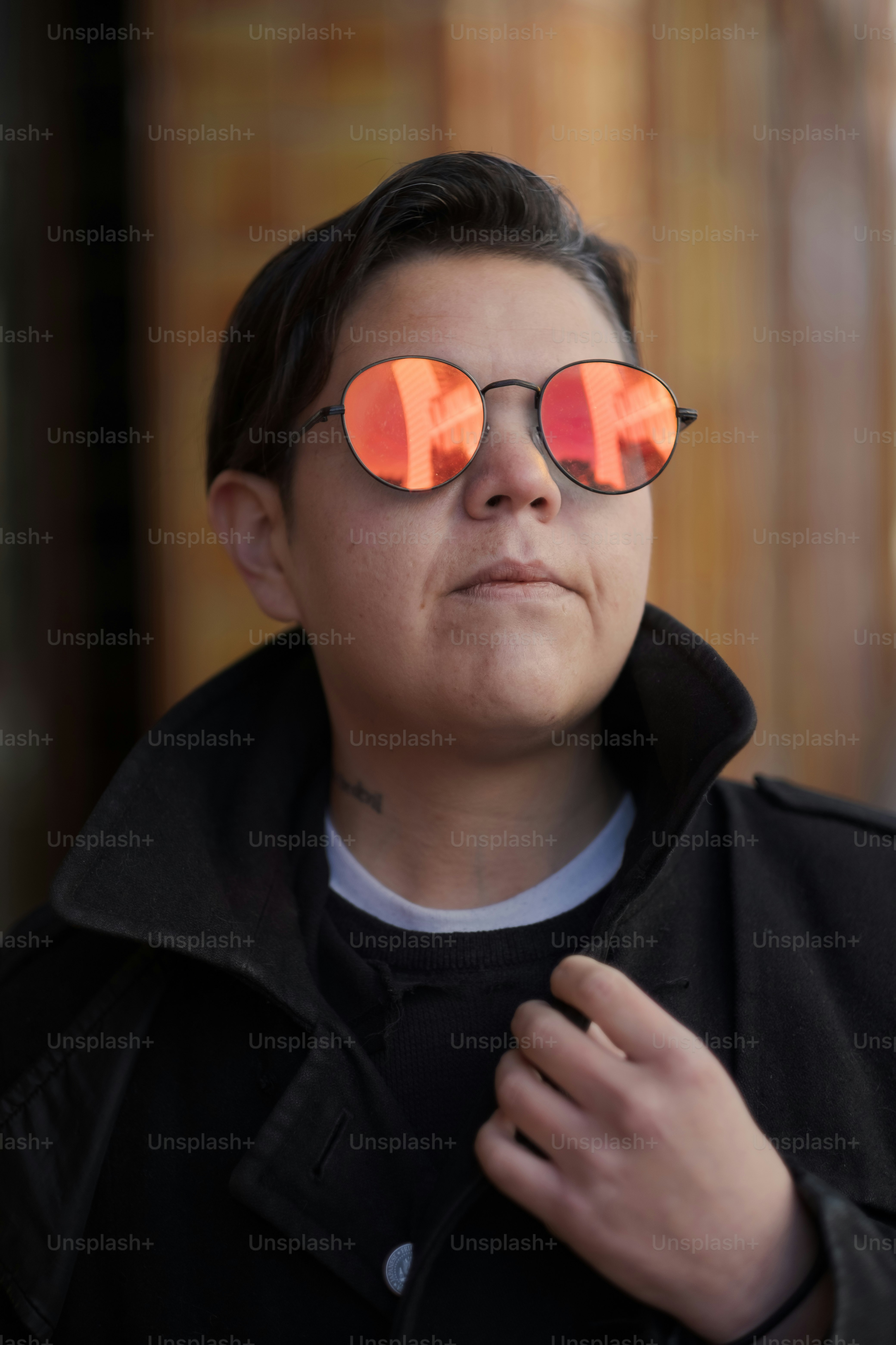 a woman wearing red mirrored sunglasses and a black jacket