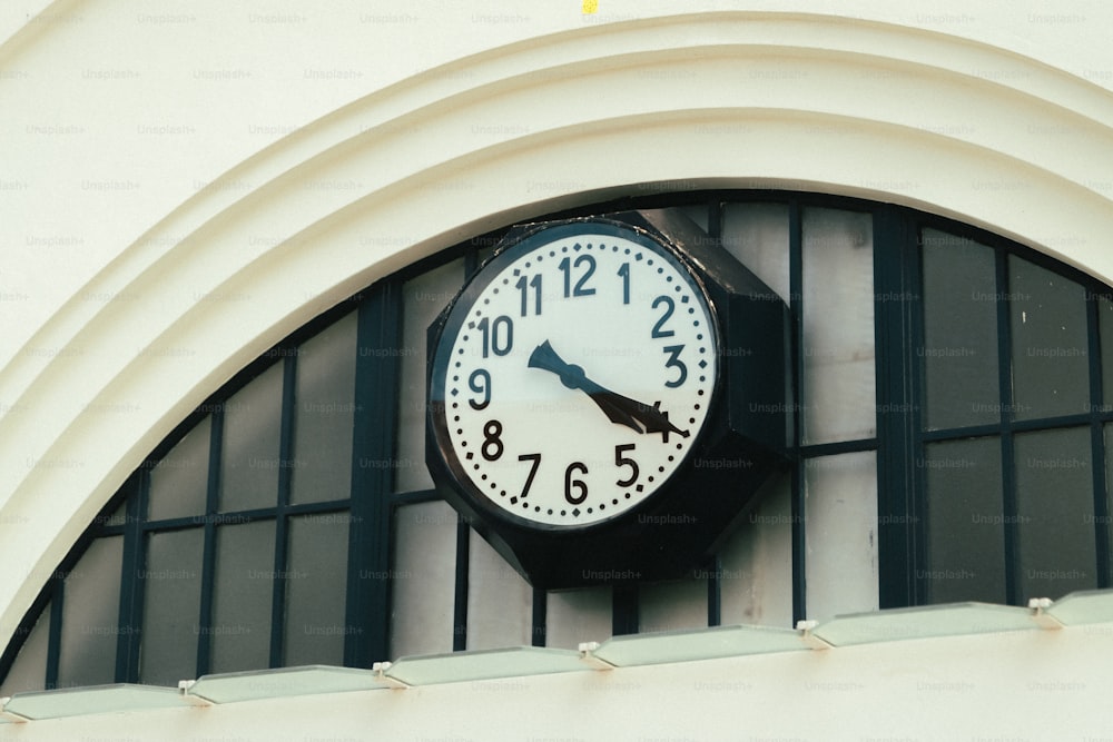 um relógio preto e branco montado ao lado de um edifício